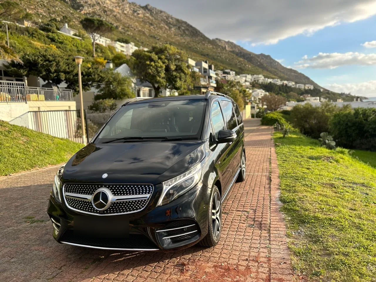 A black Mercedes-Benz V-Class on a brick road above the sea